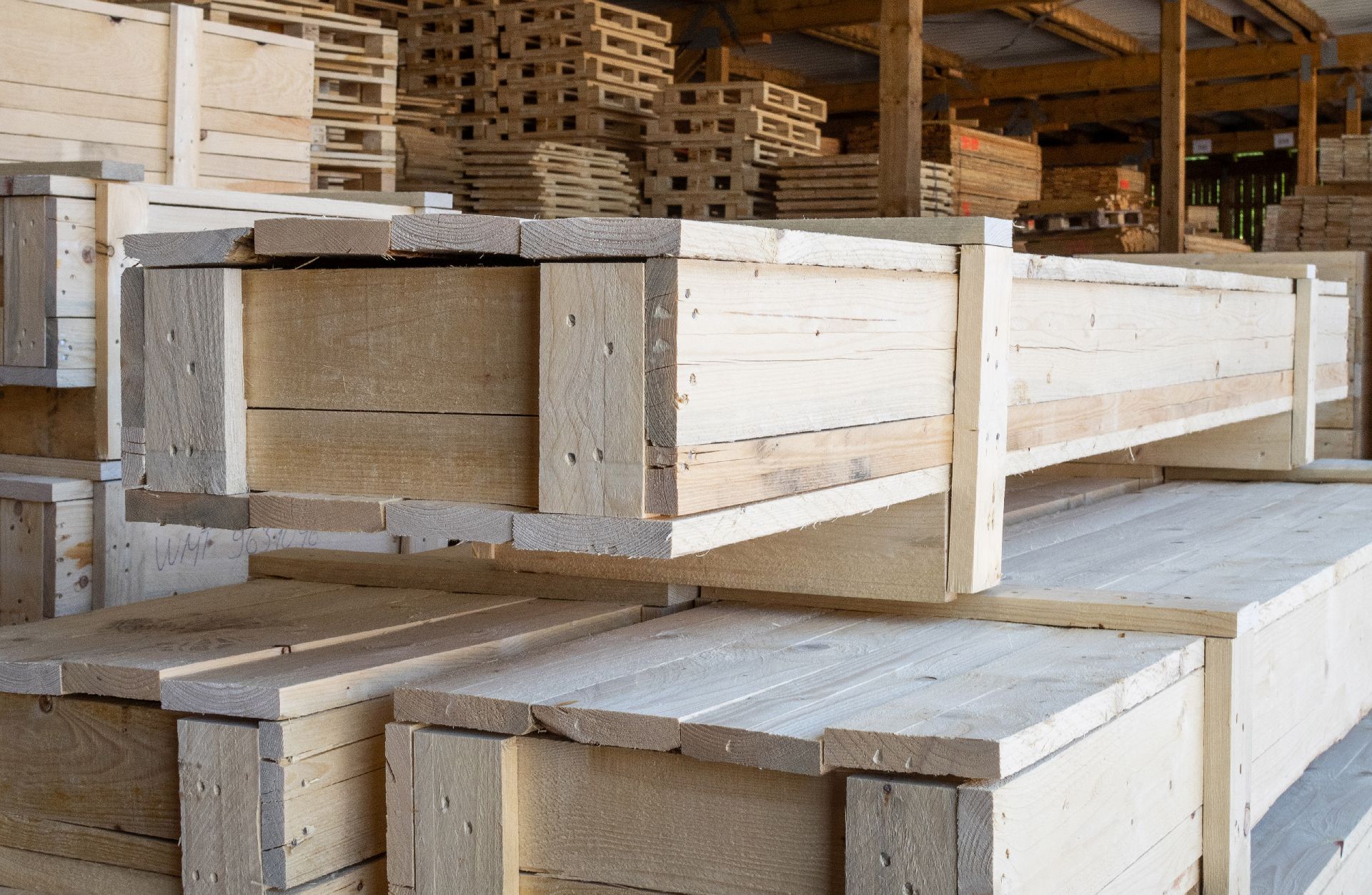 Palettenlager mit gestapelten länglichen Transportboxen aus Holz
